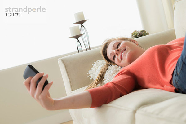 Teenagermädchen auf Sofa mit Handy  lächelnd