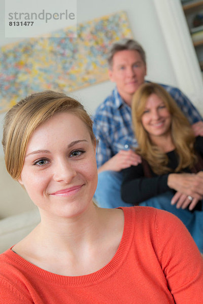 Porträt eines jungen Mädchens mit Eltern im Hintergrund