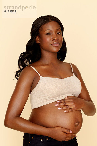 Schwangere junge Frau  die den Bauch berührt.