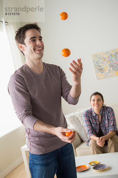 Mann jongliert mit Orangen  Frau schaut zu
