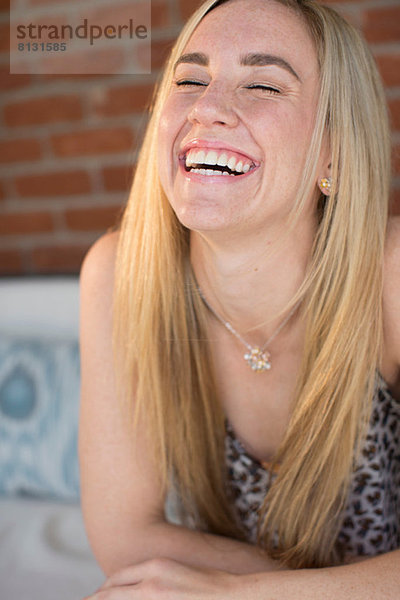 Porträt einer jungen Frau mit langen blonden Haaren  die lacht
