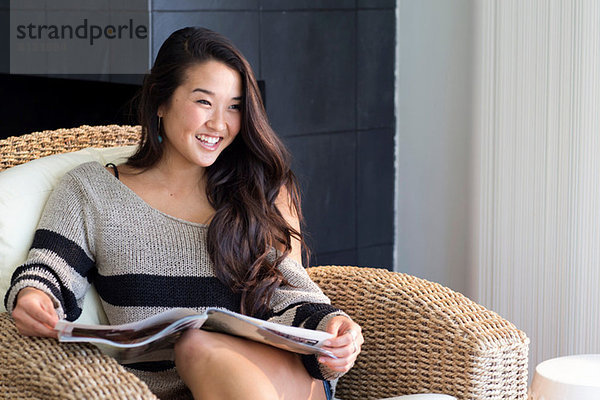 Porträt einer jungen Frau auf einem Sessel mit Magazin