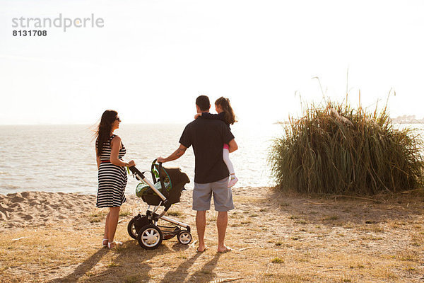 Familie am Strand stehend mit Blick aufs Meer