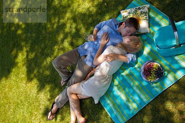 Junges Paar beim Küssen auf Picknickdecke  Draufsicht