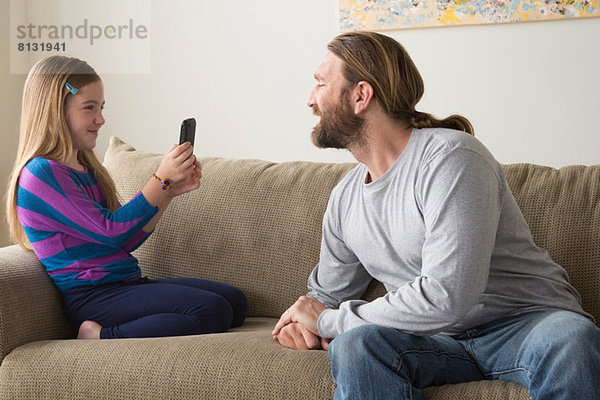 Tochter fotografiert Vater mit Smartphone