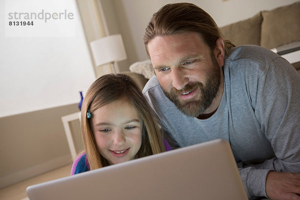 Vater und Tochter schauen auf den Laptop