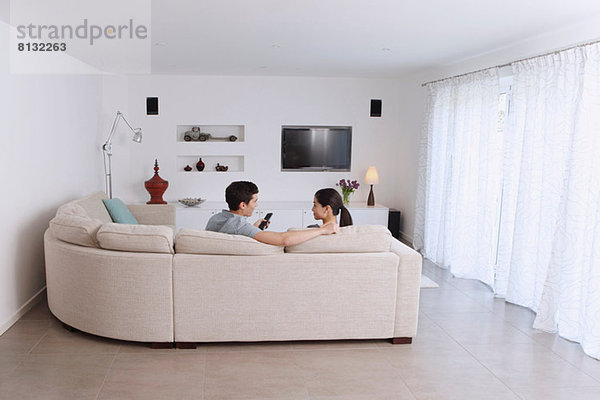 Mann und Frau entspannen sich auf dem Ecksofa im Wohnzimmer