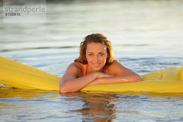 Junge Frau mit Luftmatratze in einem See