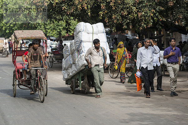 Fahrrad-Rikscha und ein Mann  der Waren auf einem Handwagen transportiert  Khari Baoli Road
