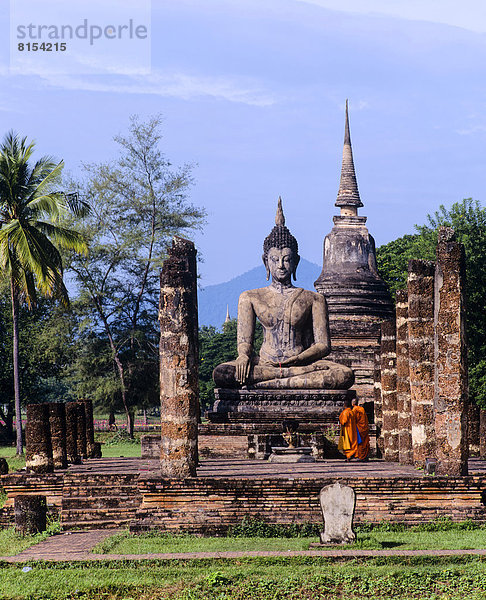Zwei Mönche vor dem sitzenden Buddha im Wat Mahathat  Tempel-Ruinen  Chedi  Geschichtspark Sukhothai