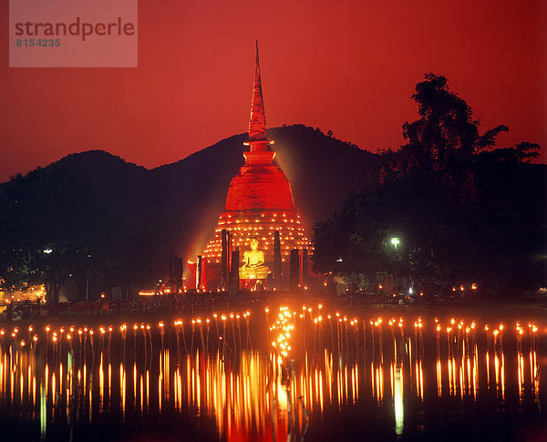 Loi Krathong Fest  Wat Sra Si in roter Beleuchtung  Fackeln spiegeln sich im Wasser  Geschichtspark Sukhothai