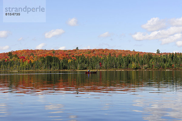 Canoe Lake mit herbstlich gefärbtem Wald und Kanufahrer