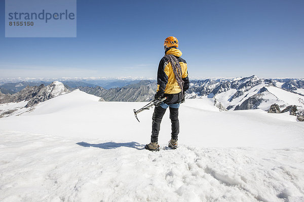 Bergsteiger steht am Gipfel des Schwarzenstein und blickt Richtung Südtirol