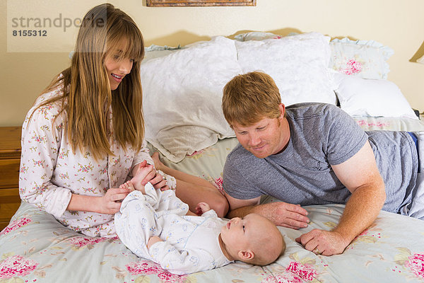 Parents with baby boy on bed  smiling