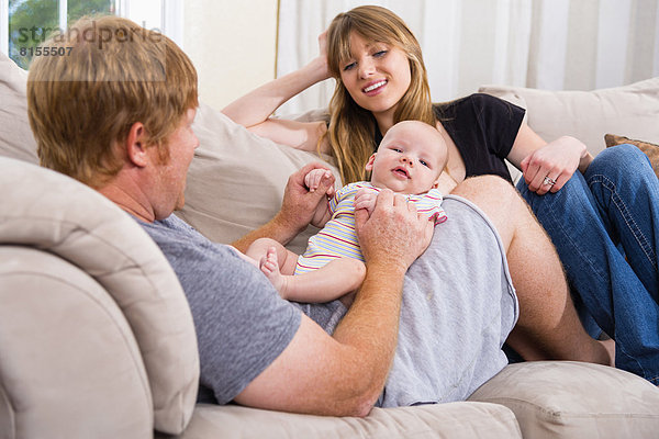 Parents with baby boy sitting on couch  smiling