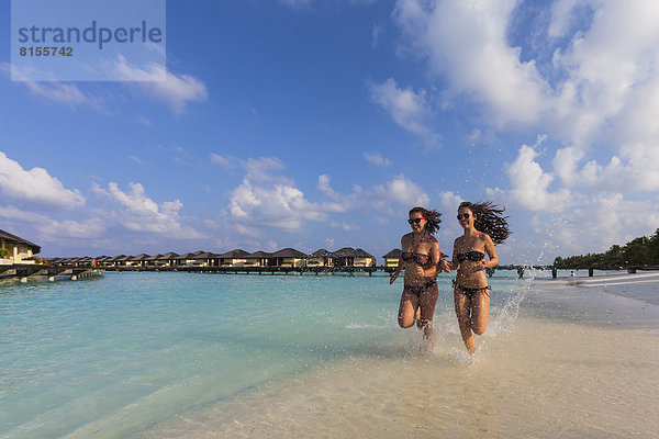 Malediven  Junge Frau und Teenagermädchen laufen am Strand