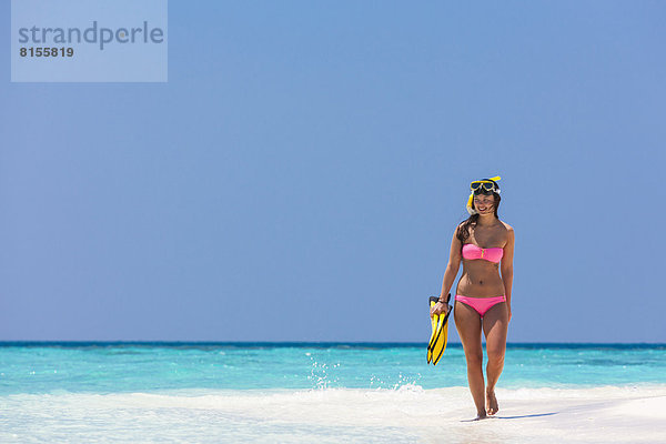 Malediven  junge Frau  die am Strand spazieren geht.