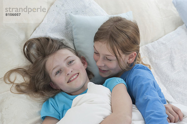 Mädchen erzählen Geheimnisse im Bett  lächelnd