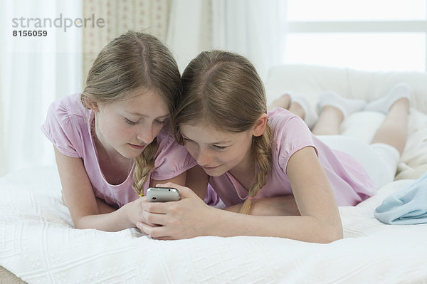 Girls using smart phone on bed  smiling