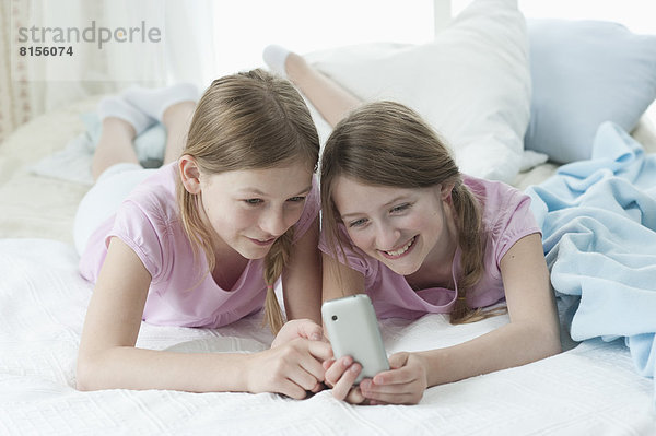 Girls using smart phone on bed  smiling