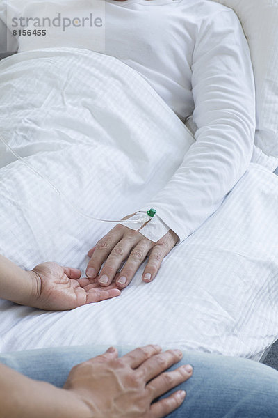 Woman holding hand of man in hospital  close up