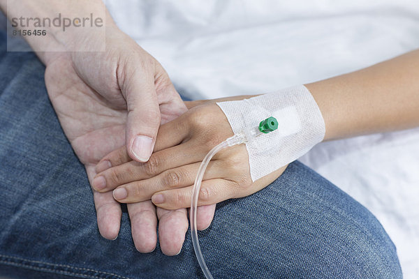 Frau hält Hand des Mannes im Krankenhaus  Nahaufnahme