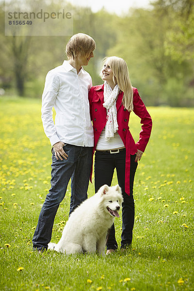 Deutschland  Junges Paar schaut sich mit Hund an  lächelnd