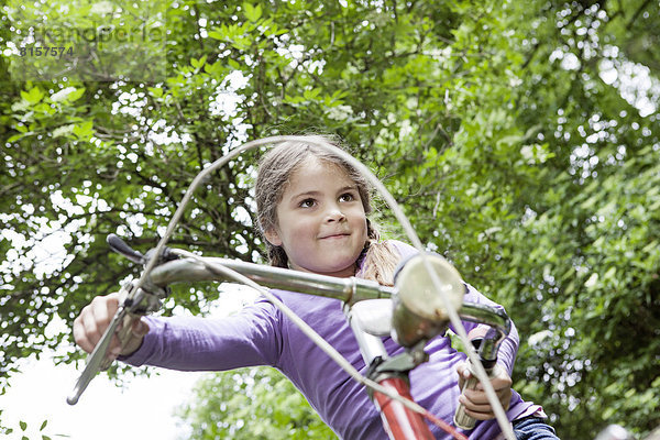 Deutschland  Nordrhein-Westfalen  Köln  Mädchen auf dem Fahrrad am Spielplatz sitzend  lächelnd