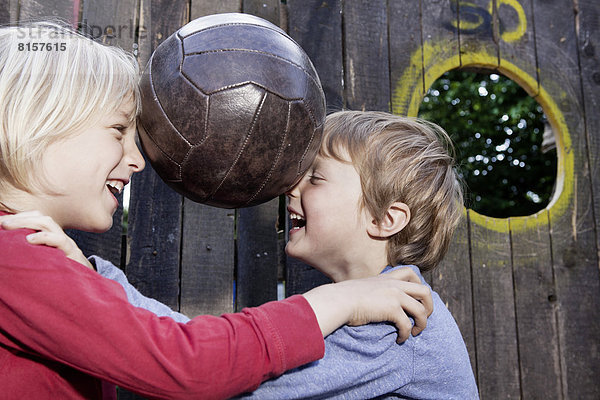 Deutschland  Nordrhein-Westfalen  Köln  Jungen spielen mit Ball im Spielplatz  lächeln