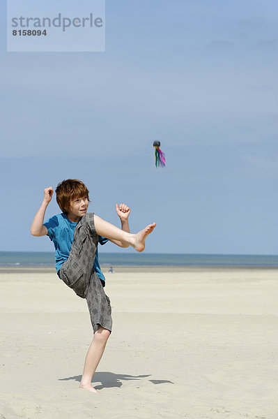 Frankreich  Junge spielt mit Indica am Strand