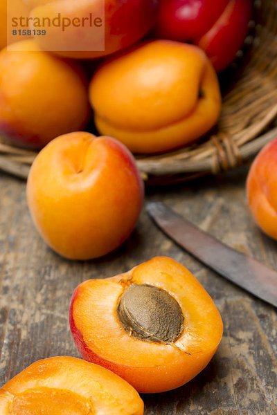 Basket of apricots with knife on wooden table  close up
