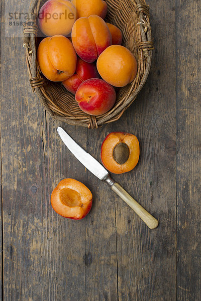 Aprikosenkorb mit Messer auf Holztisch  Nahaufnahme