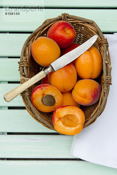 Apricots in basket with knife and napkin on table  close up