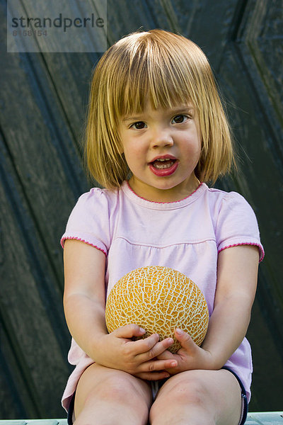 Portrait of girl holding galia melon  close up