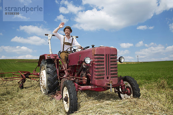 Germany  Bavaria  Farmer in tractor and waving  smiling