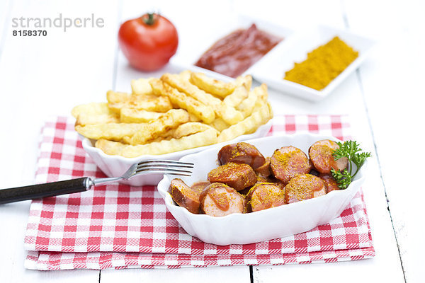 Bowl of sausages with french fries  currywurst and ketchup on wooden table  close up