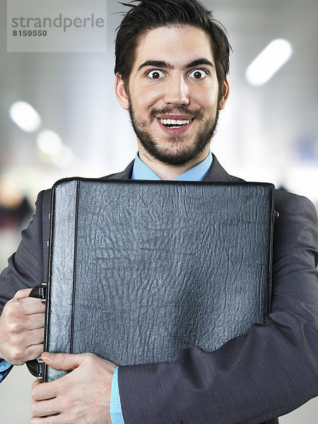 Porträt eines Geschäftsmannes mit Aktentasche am Flughafen  lächelnd