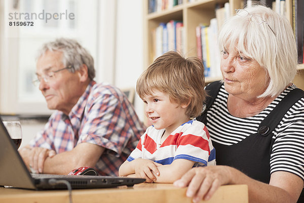 Deutschland  Berlin  Großeltern und Enkel mit Laptop  lächelnd