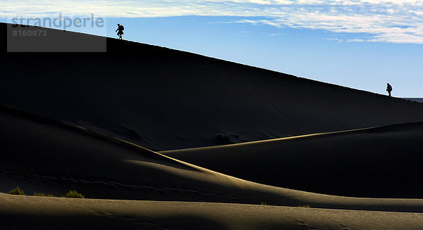 Silhouetten von Menschen auf einer Düne  Wüstenlandschaft