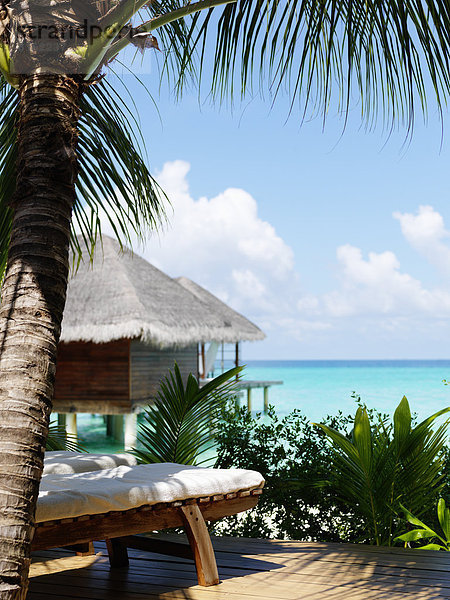 Bungalows on sandy beach  sun chair on foreground