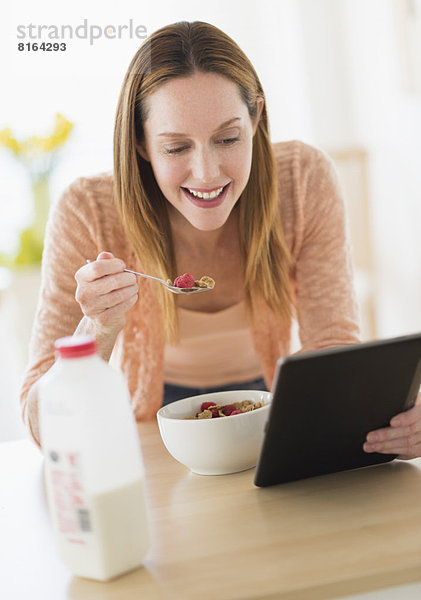 Frau  Computer  sehen  essen  essend  isst  Tablet PC  Frühstück