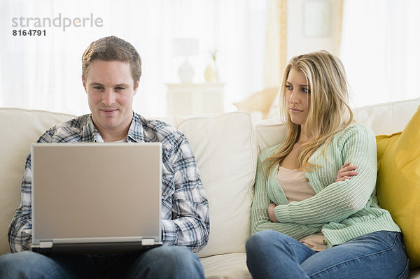Junges blondes Paar sitzt leicht bekleidet vor einem Laptop - Partnerschaft  fully_released