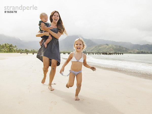 Mother with daughters (6-11 months  2-3) on beach
