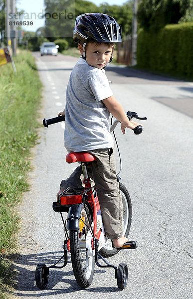 Junge fährt ein Fahrrad mit Stützrädern