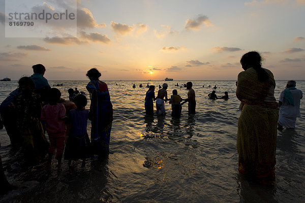 Hindu-Pilger nehmen bei Sonnenaufgang ein heiliges Bad im Meer am Ghat Agni Theertham