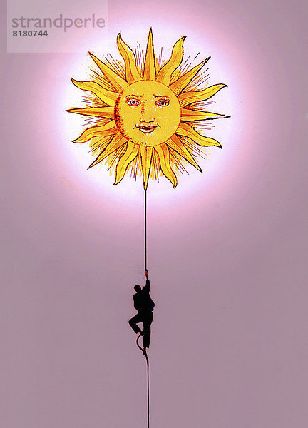 Geschäftsmann klettert auf einem Seil Richtung Sonne