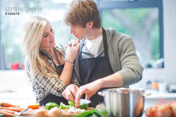 Liebevolles junges Paar beim Zubereiten von Speisen