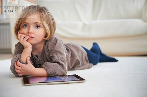 Auf dem Boden liegendes Mädchen mit digitalem Tablett