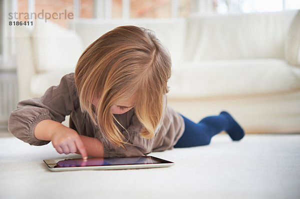 Auf dem Boden liegendes Mädchen mit digitalem Tablett