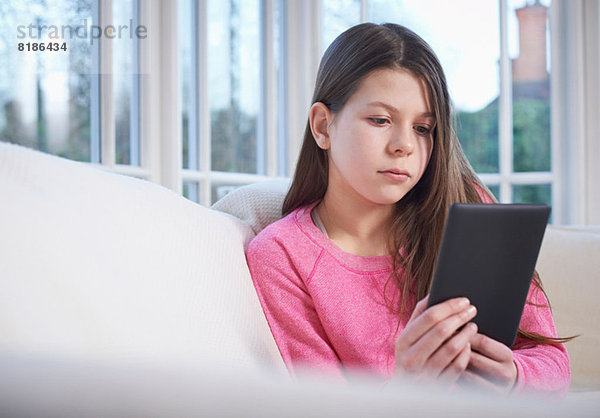 Mädchen mit digitalem Tablett auf dem Sofa